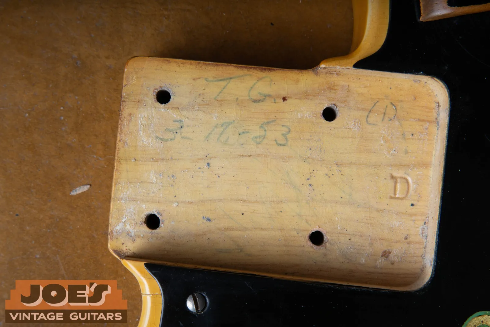 The neck pocket of an early 1950s Fender Precision Bass, penciled 3-17-53 with a worker's initials T.G. above the date and a stamped D