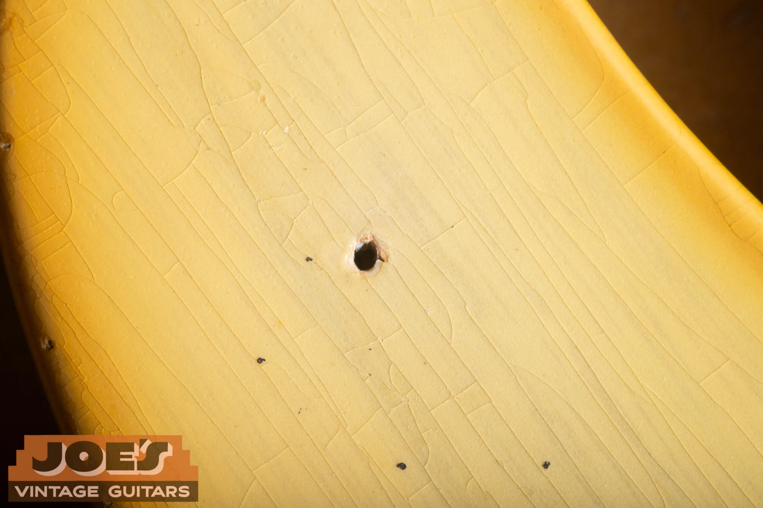 Nail holes in a 1952 Fender Precision Bass finish showing bare wood at center, the nail was removed after spraying, leaving a clean hole through the lacquer to bare wood