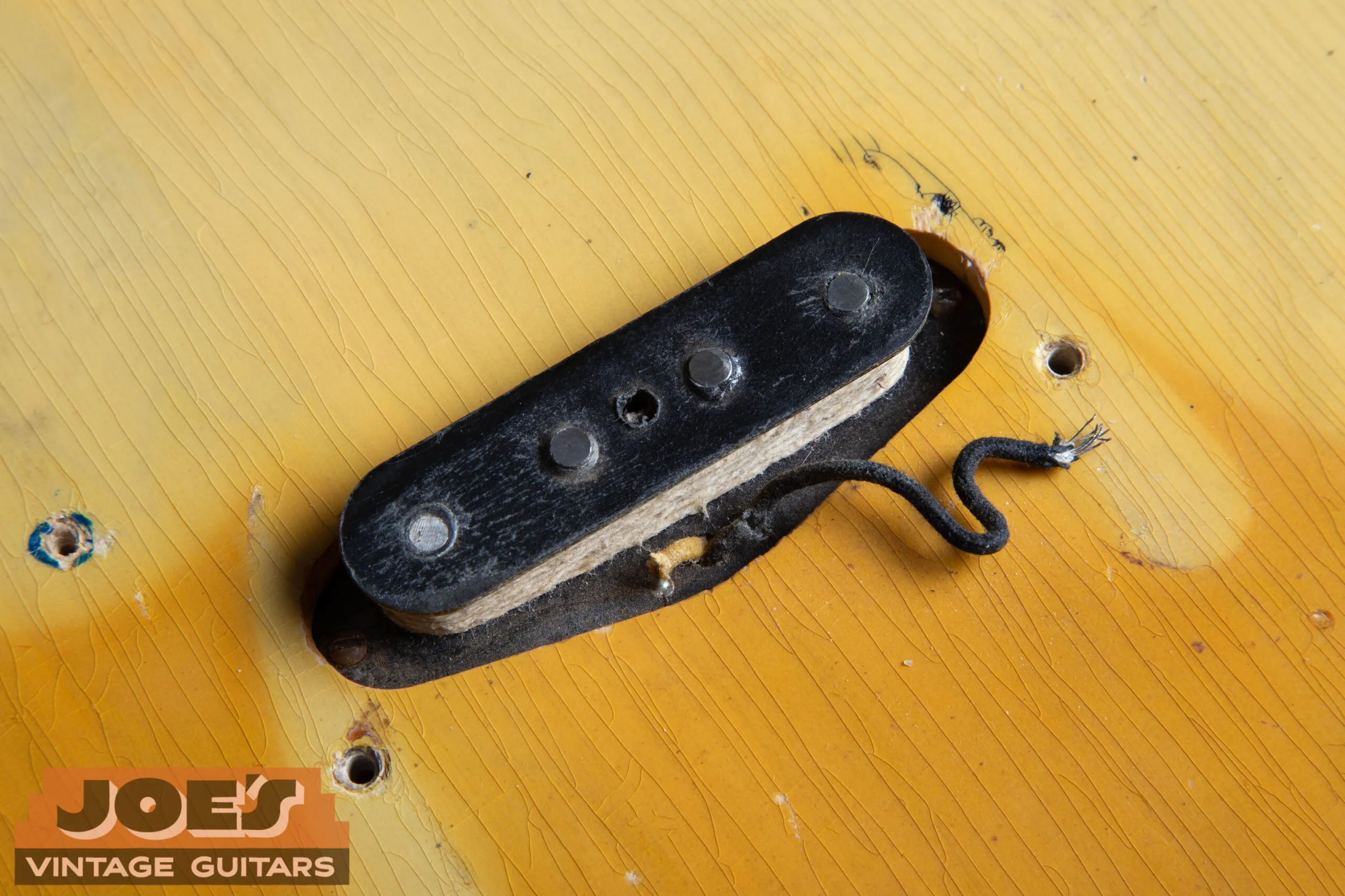 Original early-style single-coil pickup on a 1952 Fender Precision Bass showing white string wrapping over the coil windings