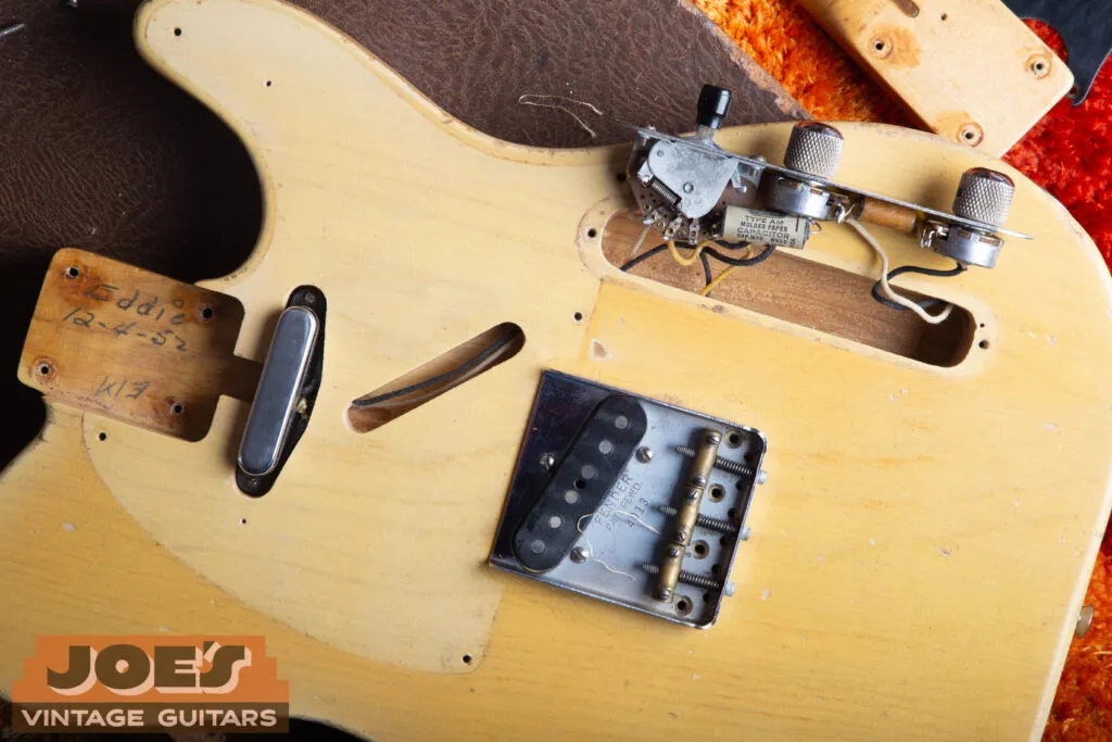 Pale unfaded wood revealed under the lifted pickguard of a 1952 Fender Telecaster, next to the darker butterscotch of the exposed body