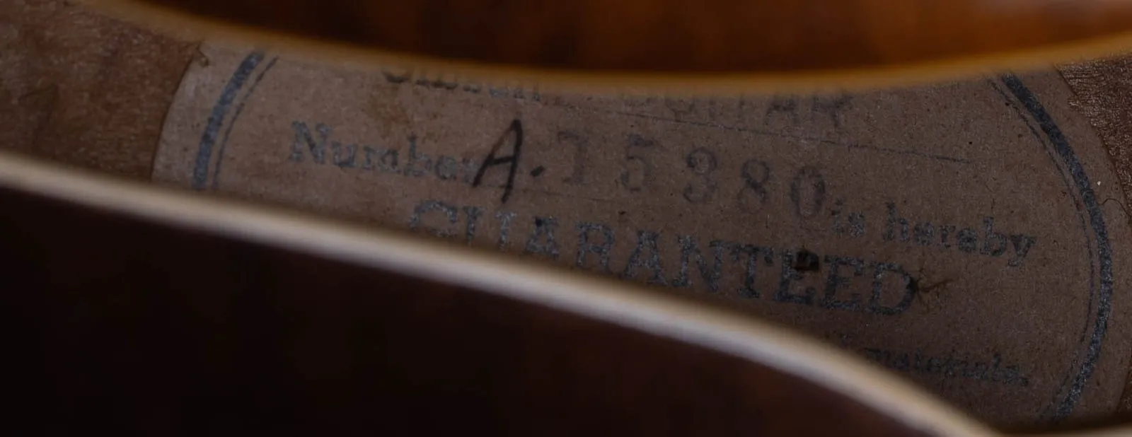 A white oval Gibson guarantee label reading serial number A-15380 inside a 1953 ES-5.