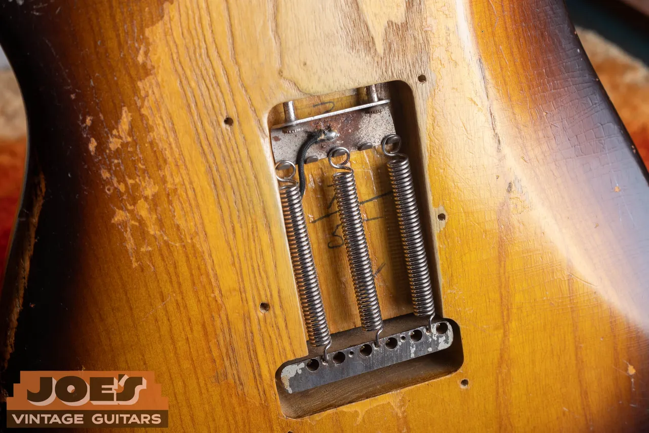 The rear spring cavity of a 1955 Fender Stratocaster with the back plate removed, the body date behind the tremolo springs