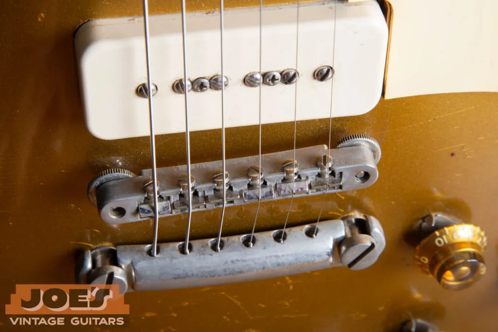Top-down close-up of a 1956 Gibson Les Paul ABR-1 Tune-o-matic bridge, highlighting the “no-wire” design with nickel-plated saddles and thumbwheels.
