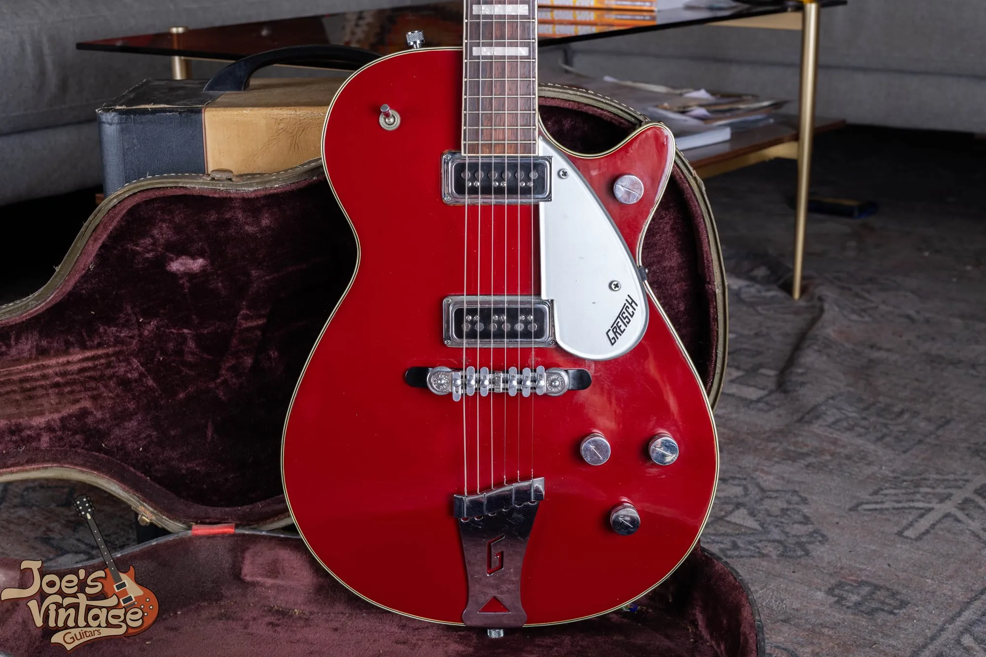 Front of a 1956 Gretsch Jet Fire Bird 6131 with a red top, two DeArmond Dynasonic pickups, and a Melita Synchro-Sonic bridge, in its original case.