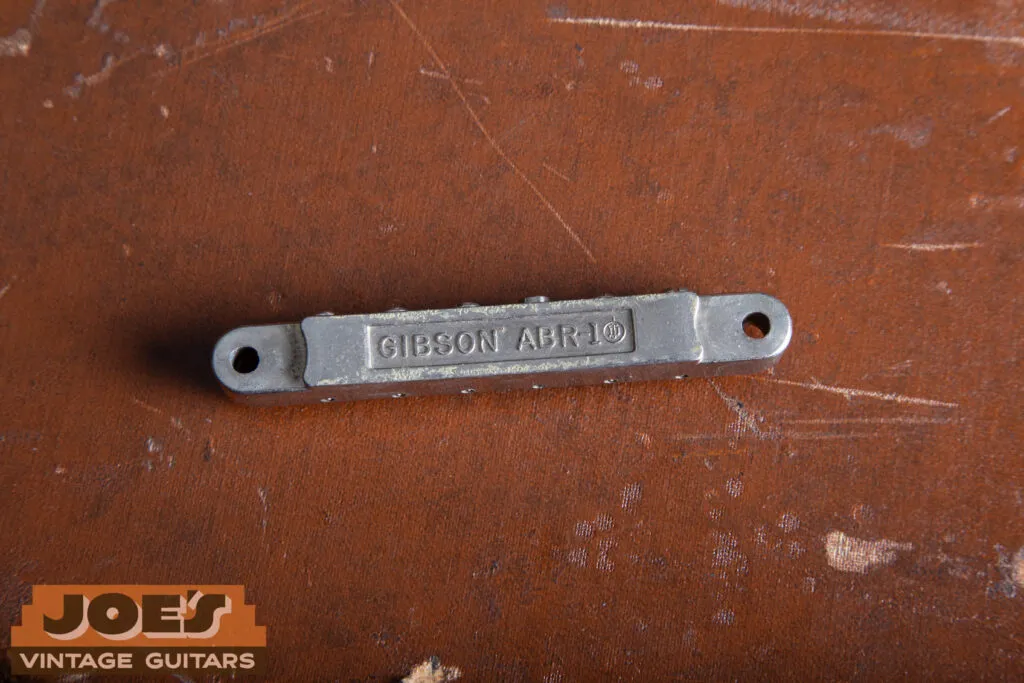 Macro close-up of the underside of an original nickel-plated ABR-1 Tune-o-matic bridge, showing the “ABR-1” stamp and the absence of a retainer wire.