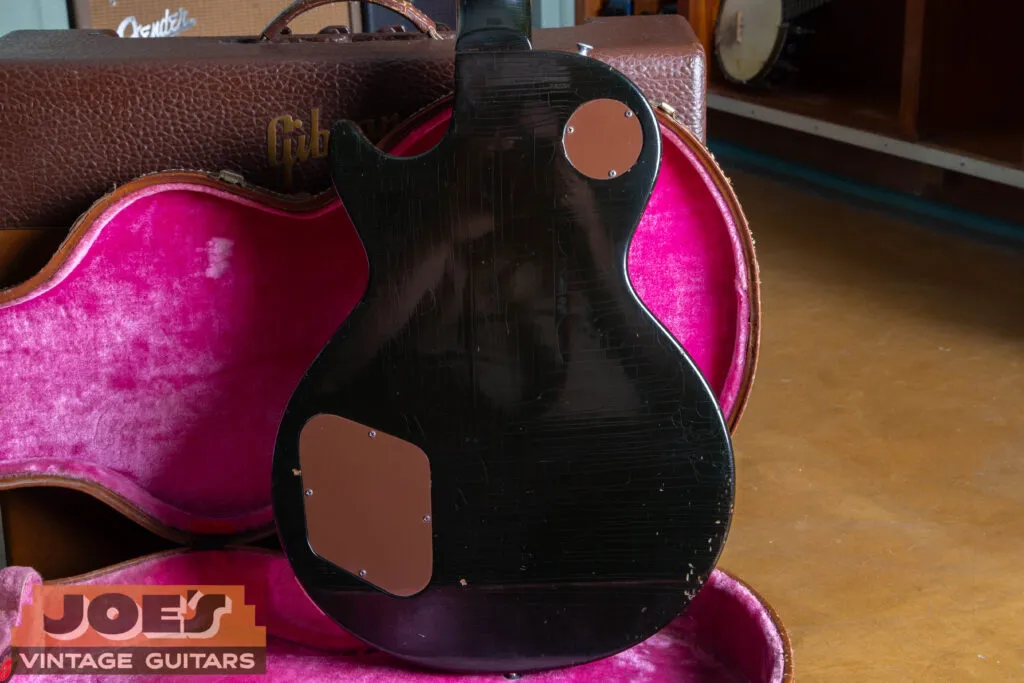 Alt TextA deep, translucent “Dark Back” finish on a 1957 Gibson Les Paul, showcasing the exceptionally dark chocolate-brown mahogany stain that allows the natural wood grain to remain subtly visible under direct light.