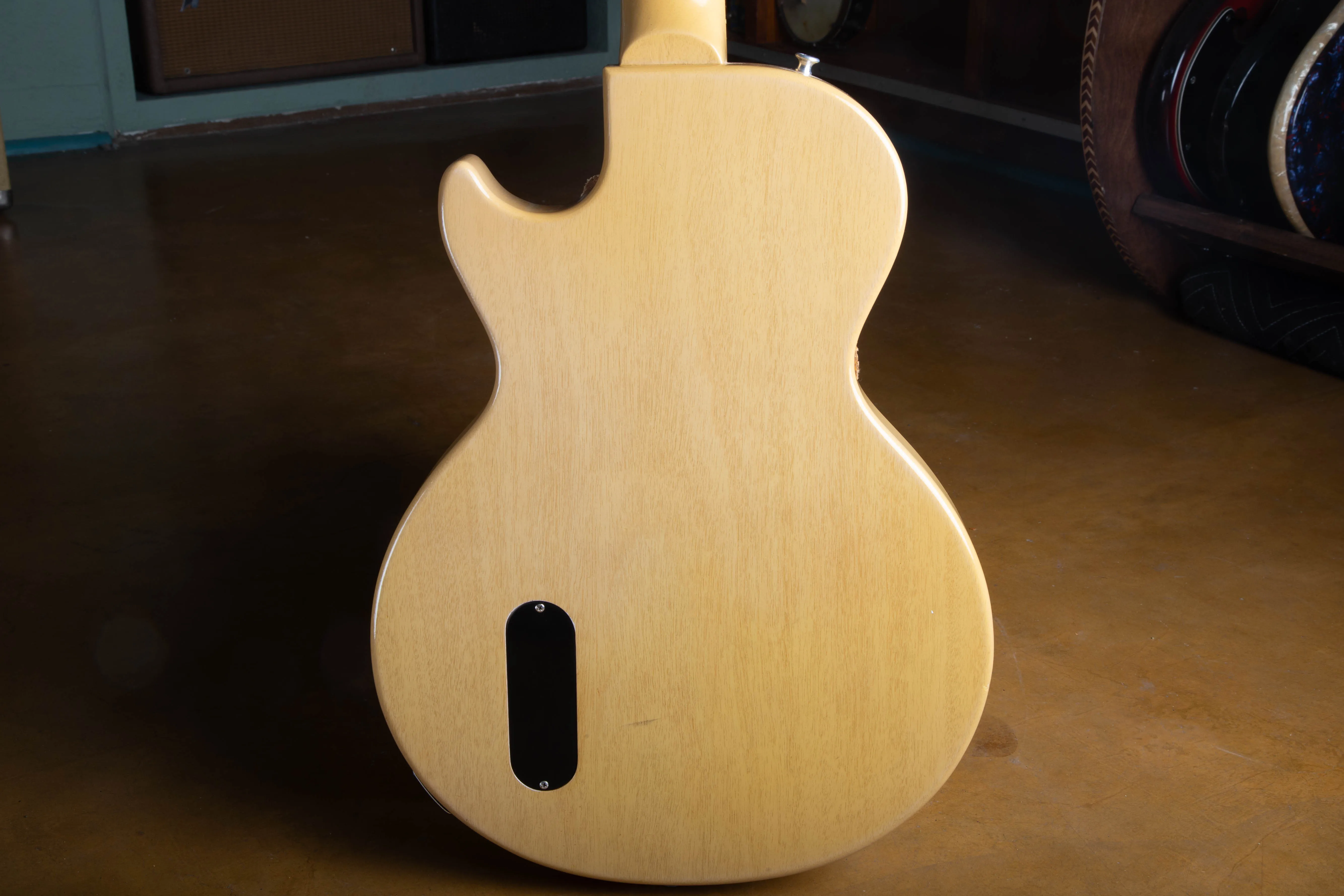Back of the body of a 1957 Gibson Les Paul TV Model, showing the translucent limed mahogany finish over the solid mahogany slab body with the wood grain clearly visible through the pale yellow lacquer, plus the black plastic oval control cavity cover.