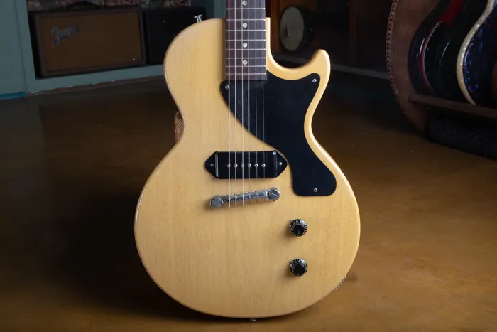 Front of a 1957 Gibson Les Paul TV Model in TV Yellow limed mahogany finish, showing the single black dog-ear P-90 pickup, single-ply black pickguard, one-piece wraparound bridge, and two black bonnet knobs.