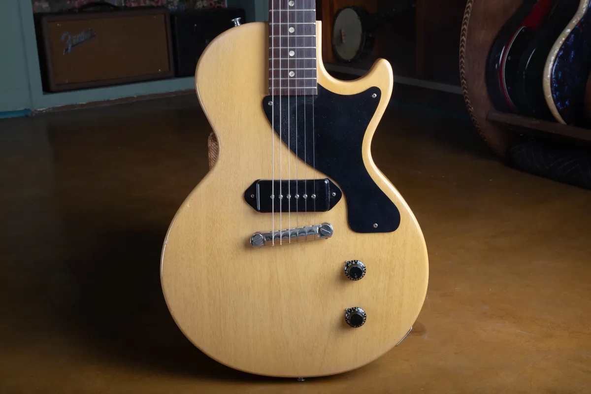 Front of a 1957 Gibson Les Paul TV Model in TV Yellow limed mahogany finish, showing the single black dog-ear P-90 pickup, single-ply black pickguard, one-piece wraparound bridge, and two black bonnet knobs.