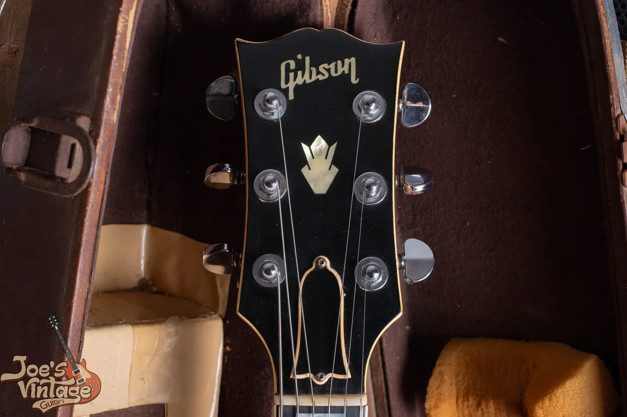 Headstock of a 1958 Gibson ES-5 Switchmaster showing the gold Gibson logo and the pearl crown inlay on a bound black headstock.
