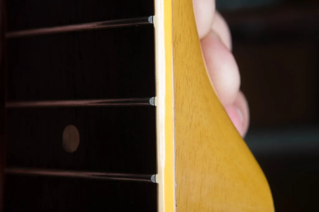 Detailed side-profile view of the neck binding on a 1958 Gibson Les Paul Special. The image shows the original “fret nibs,” where the plastic binding material rolls up to cover the ends of the frets. This feature confirms the instrument has its factory-original frets, as the nibs are typically lost during a professional refret.