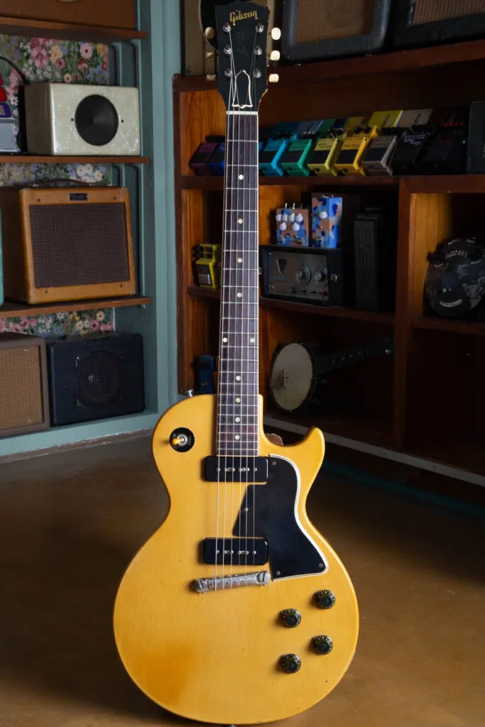 Full-body studio photograph of a 1958 Gibson Les Paul Special in its original TV Yellow (limed mahogany) finish. The single-cutaway mahogany slab body is shown from the front, highlighting the dual P-90 soapbar pickups, wraparound tailpiece, black “top hat” knobs, and the 5-ply pickguard. The bound mahogany neck and headstock with original Kluson strip tuners complete the factory-correct silhouette of this “Golden Era” instrument.