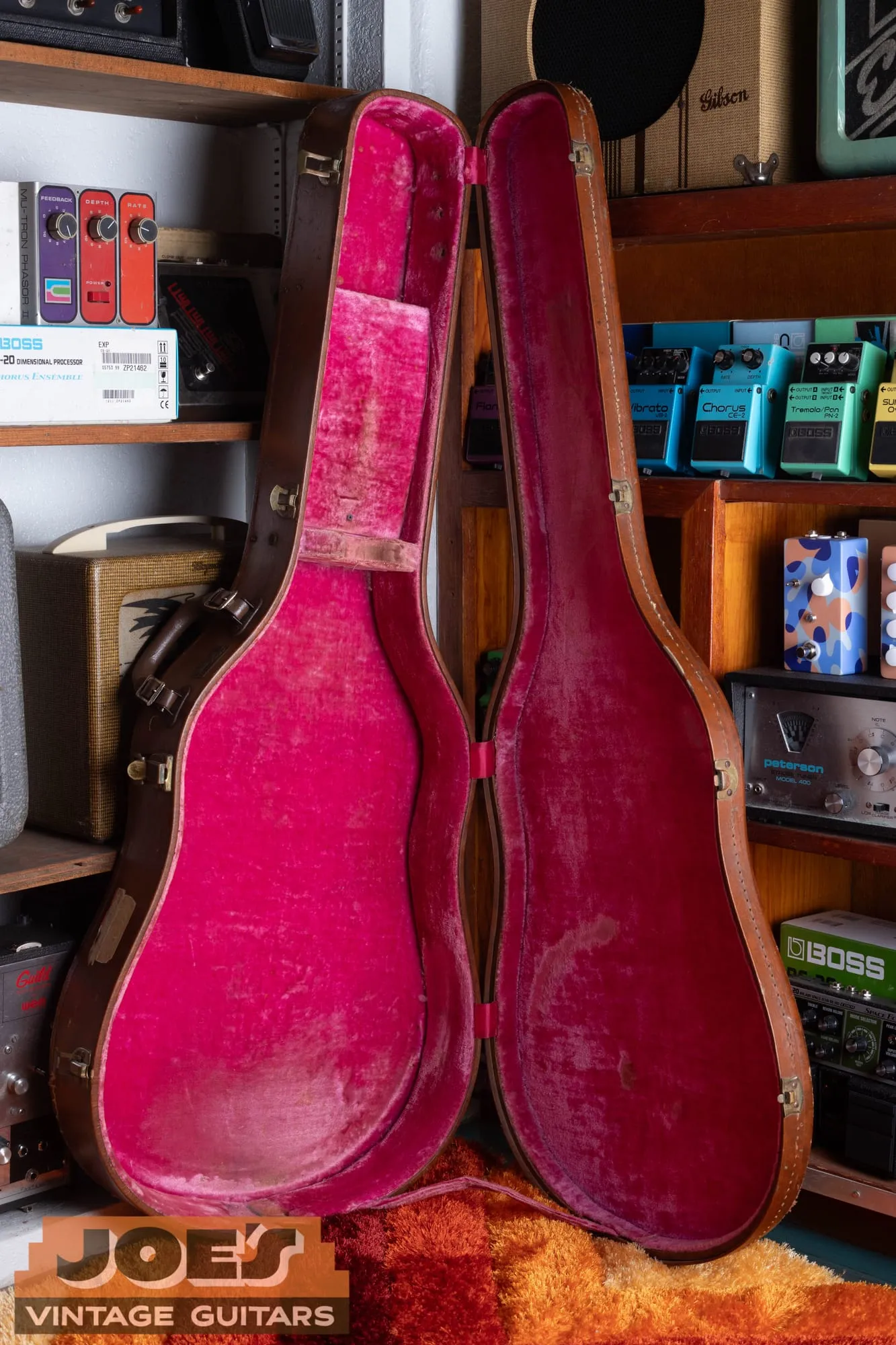 Full back of a 1959 Gibson ES-355 in cherry standing in its open brown case with pink lining.