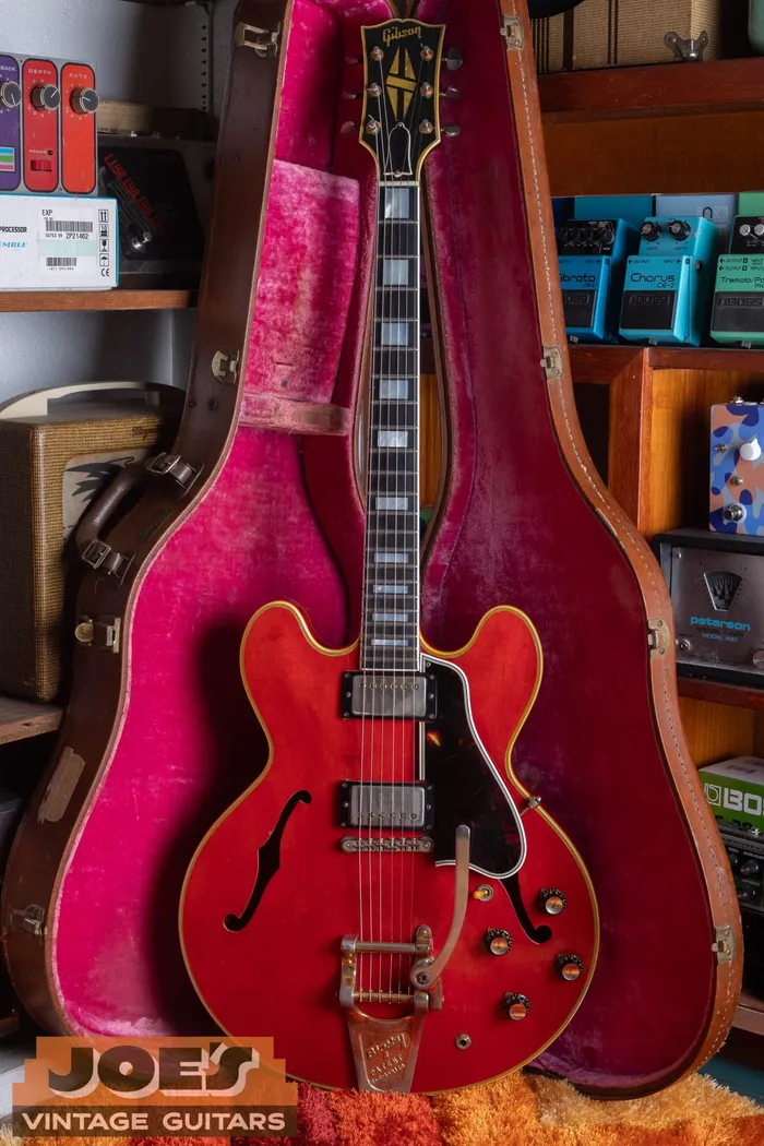 Front of a 1959 Gibson ES-355 in cherry red with a Bigsby vibrato, split-diamond headstock, and gold hardware, resting in its pink-lined case at Joe's Vintage Guitars.