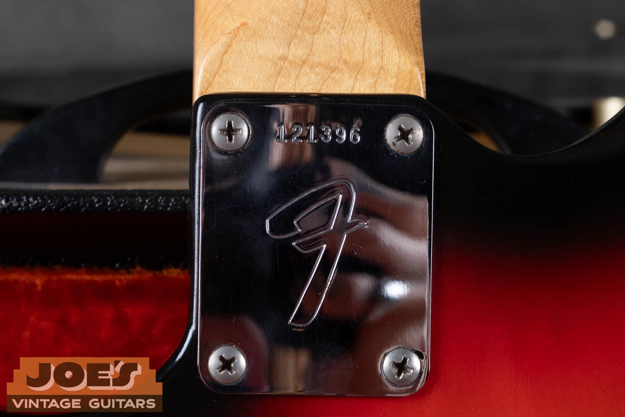 Fender Jazzmaster CBS-era F-logo neck plate with serial number, large stylized F on chrome neck plate indicating post-1965 CBS production