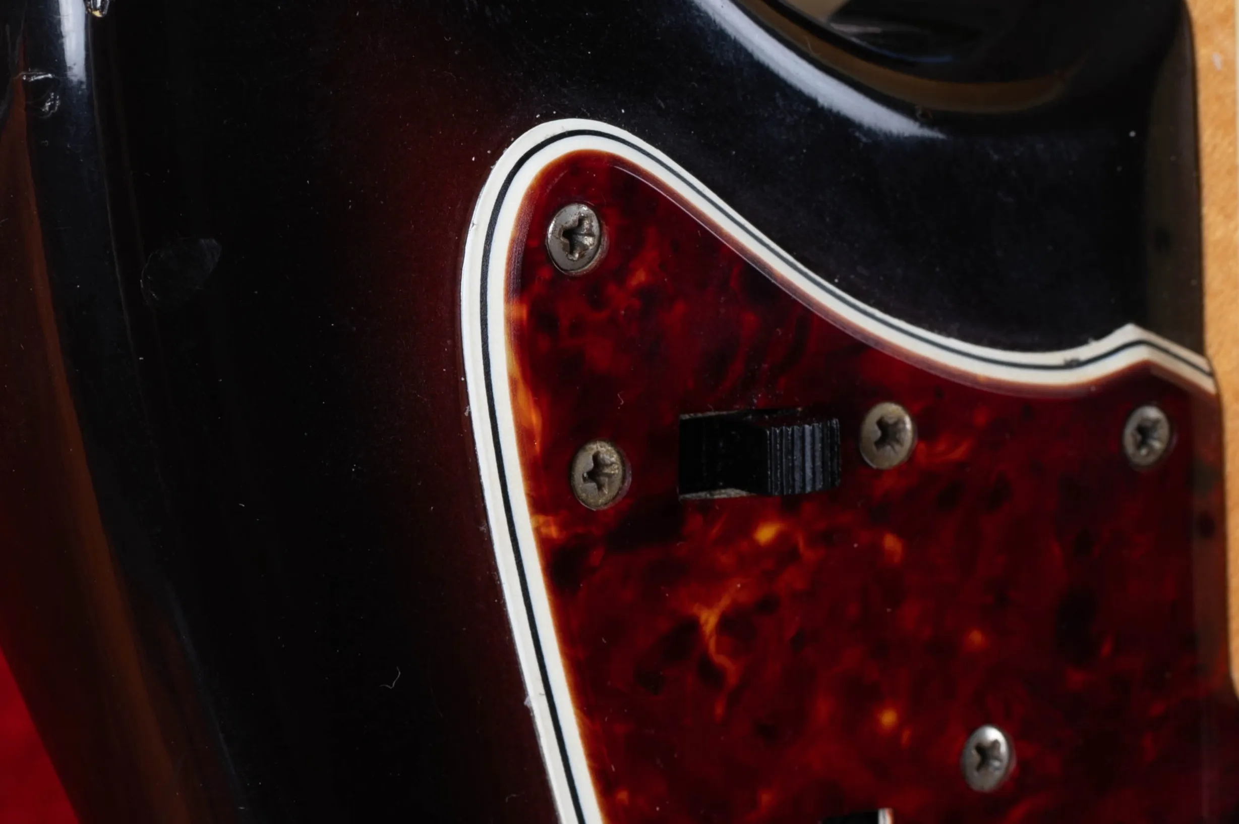 Fender Jazzmaster multi-ply tortoiseshell pickguard layers close-up, 4-layer construction showing tortoiseshell white black white laminate at cut edge