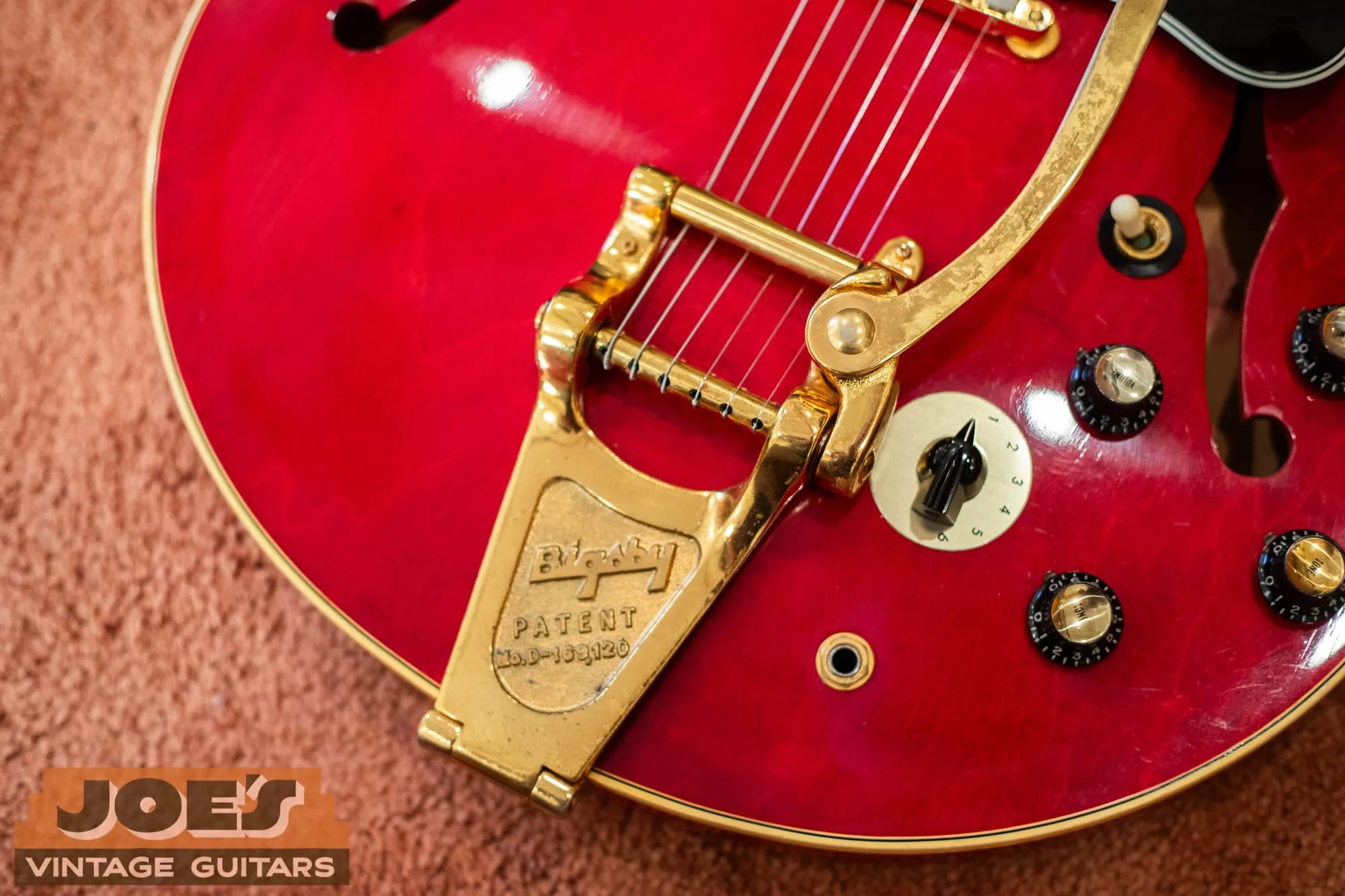 Close-up of a gold Bigsby vibrato tailpiece stamped Bigsby Patent No. D-169,120 and the Varitone dial on a 1966 Gibson ES-345 in cherry.
