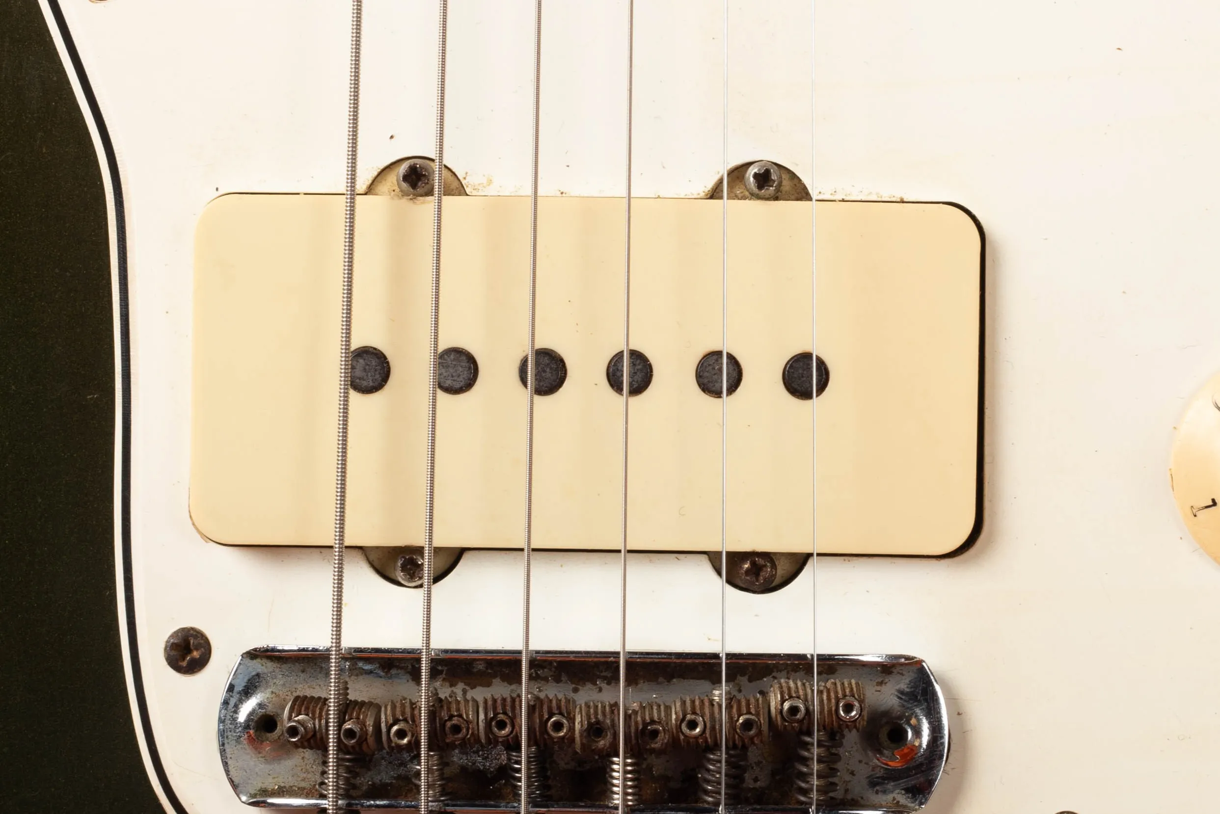 Fender Jazzmaster pickup close-up, wide flat single-coil pickup with white plastic cover flush-mounted to pickguard, six level pole pieces visible from above, 1966 CBS-era example
