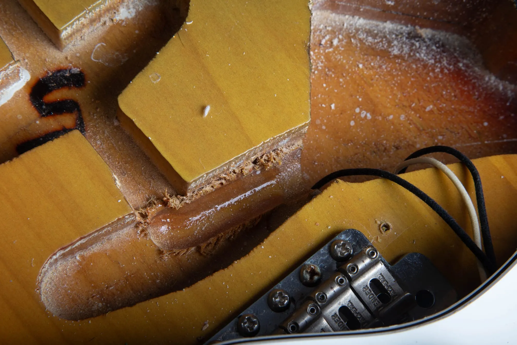 Close-up of the internal routing inside a 1967 Fender Stratocaster body, showing original nitrocellulose finish reaching into the cavity edges and bare wood in the rout channel.