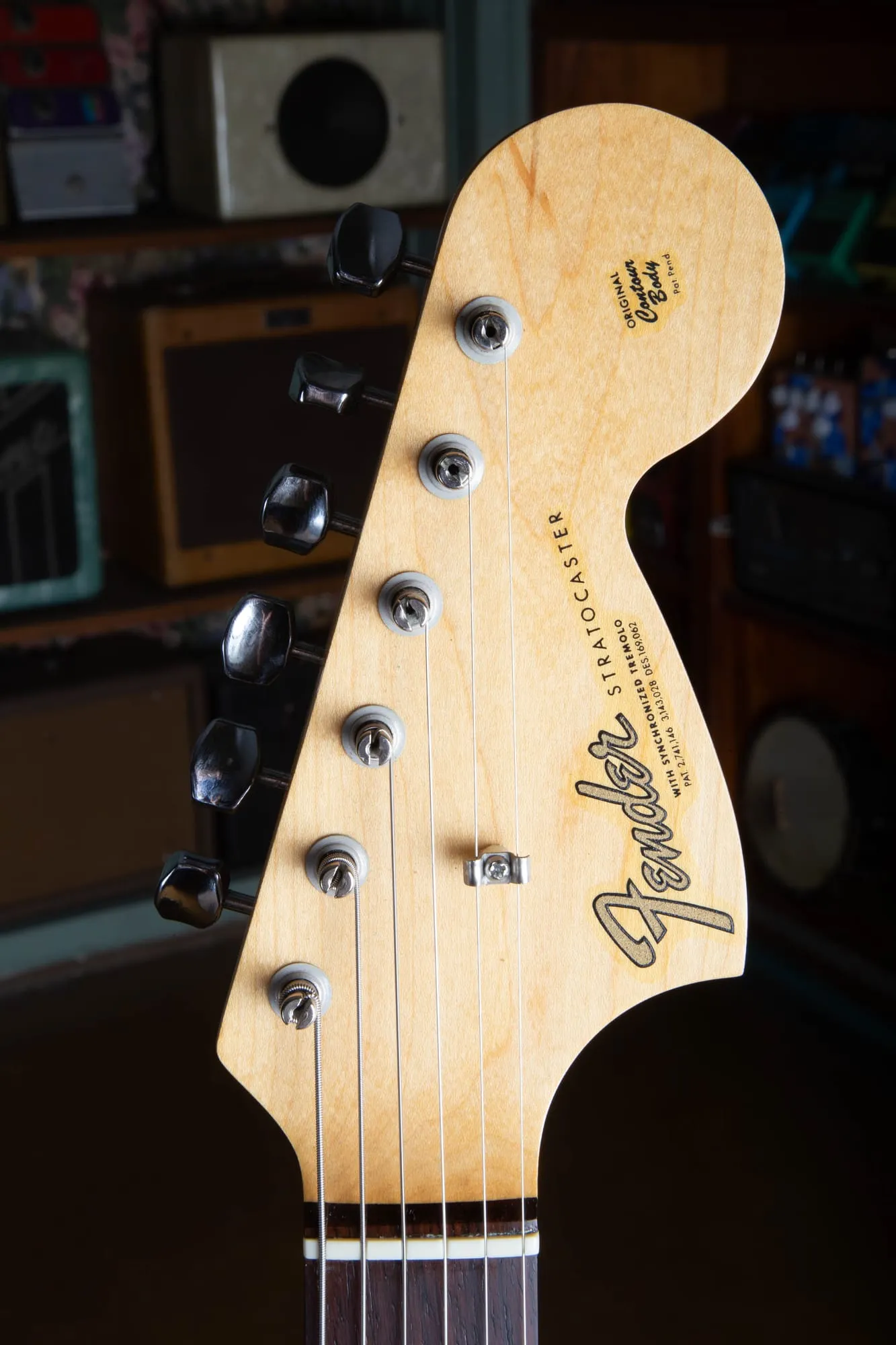 Front of the large CBS headstock on a 1967 Fender Stratocaster, showing the gold transition Fender Stratocaster logo, patent numbers, With Synchronized Tremolo text, Original Contour Body decal, and a single butterfly string tree.