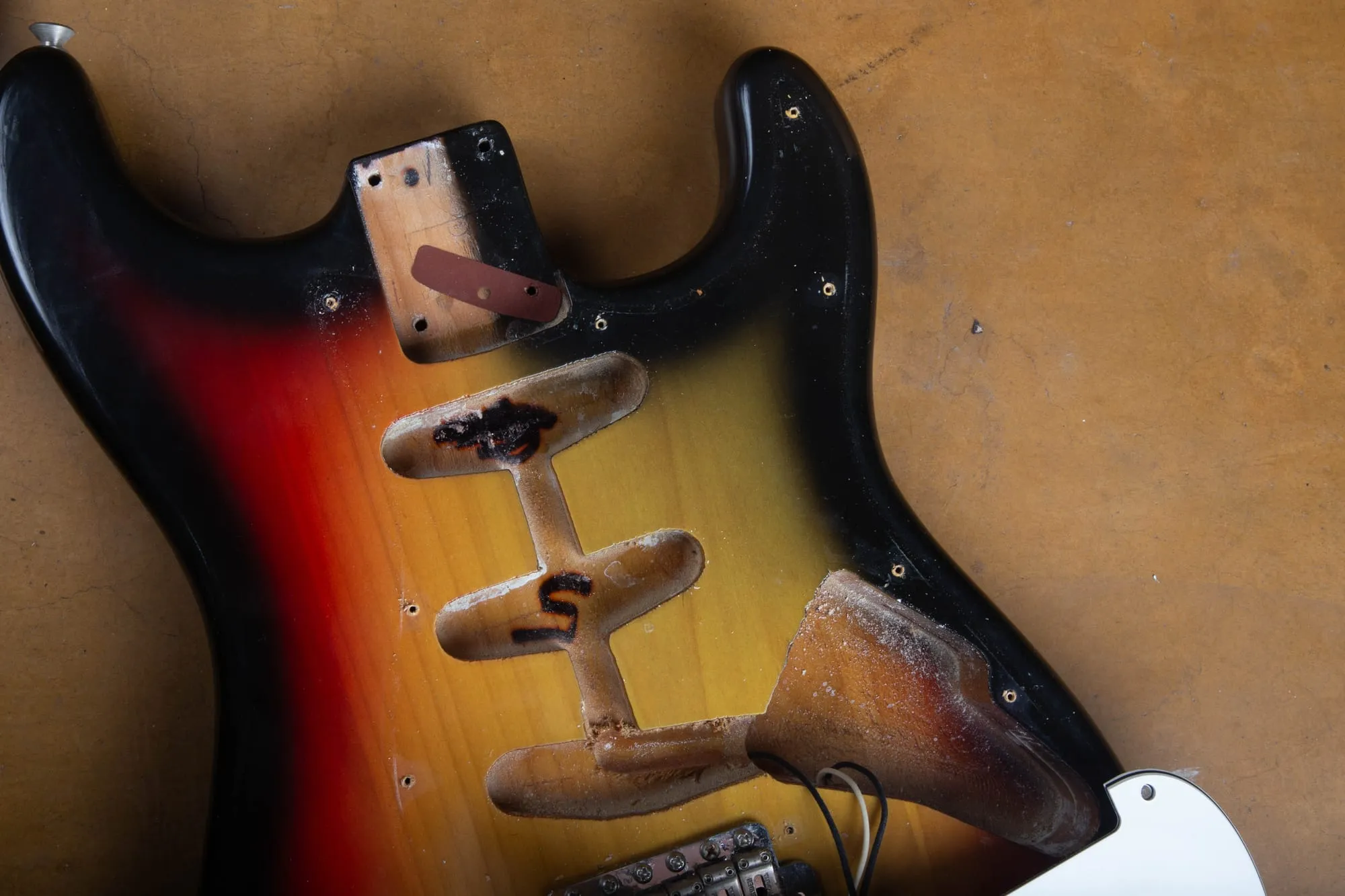 Neck pocket and tremolo cavity of a 1967 Fender Stratocaster body, showing the pickup routes, spring cavity, dark red neck shim, and worn nitrocellulose finish through to bare wood.