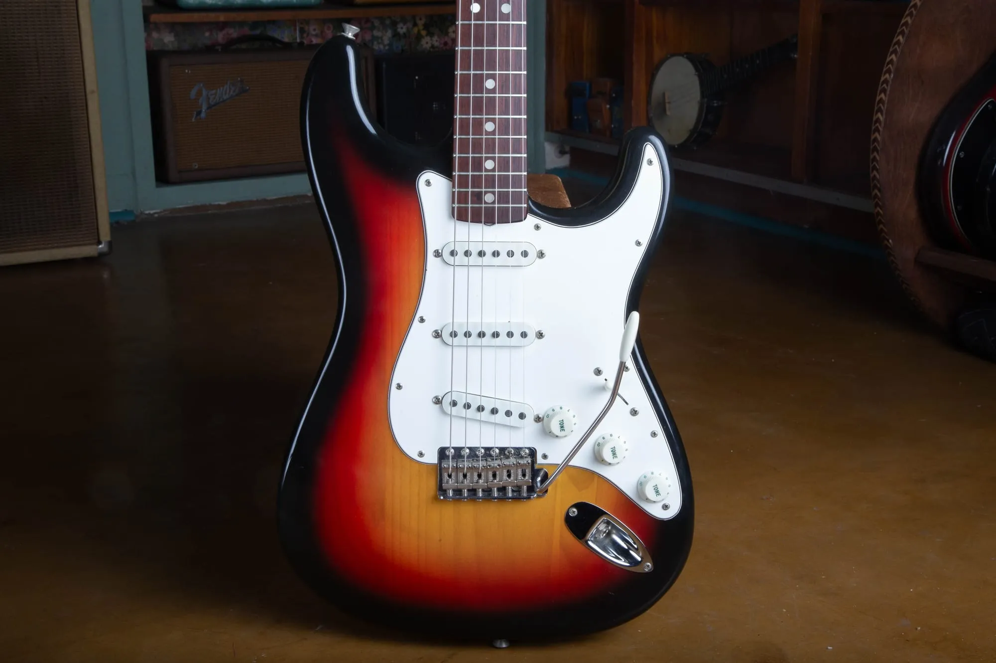 Front of a 1967 Fender Stratocaster body in three-tone sunburst, showing the rosewood fingerboard, aged white three-ply pickguard, three single-coil pickups, and synchronized tremolo bridge.