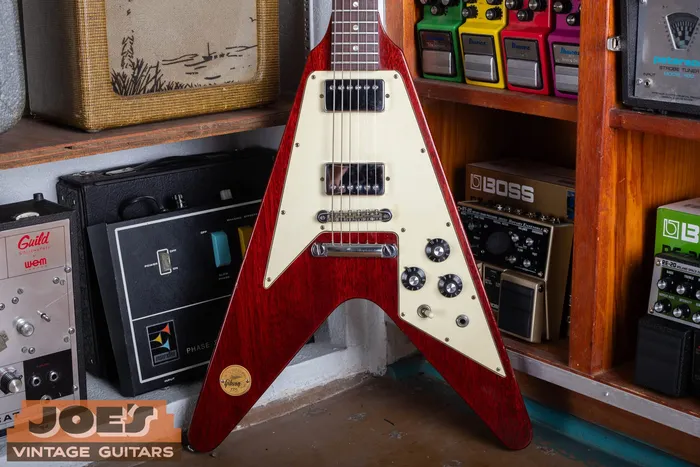 A cherry 1971 Gibson Flying V Medallion leaning in the shop, showing the large cream pickguard, two chrome humbuckers, and the small gold limited-edition medallion set into the lower bass wing.