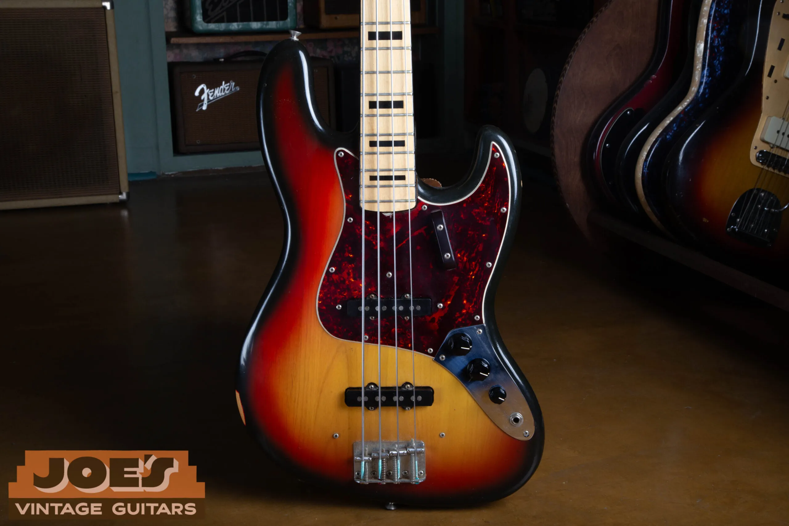 Close-up of the 1973 Fender Jazz Bass body in 3-color sunburst showing both single-coil pickups, the chrome control plate with period-correct knobs, and tortoise pickguard
