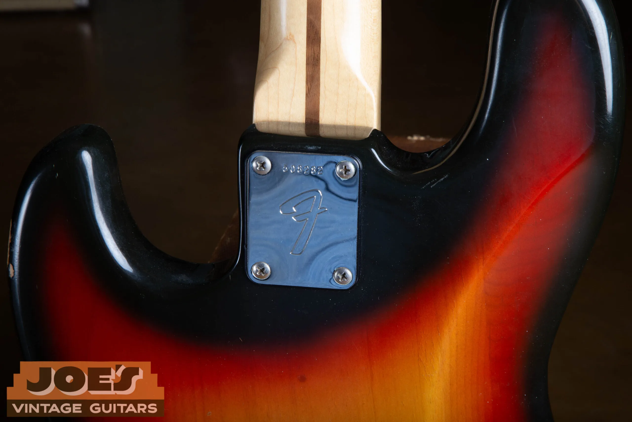 The neck plate of a 1973 Fender Jazz Bass showing the stamped serial number on chrome.