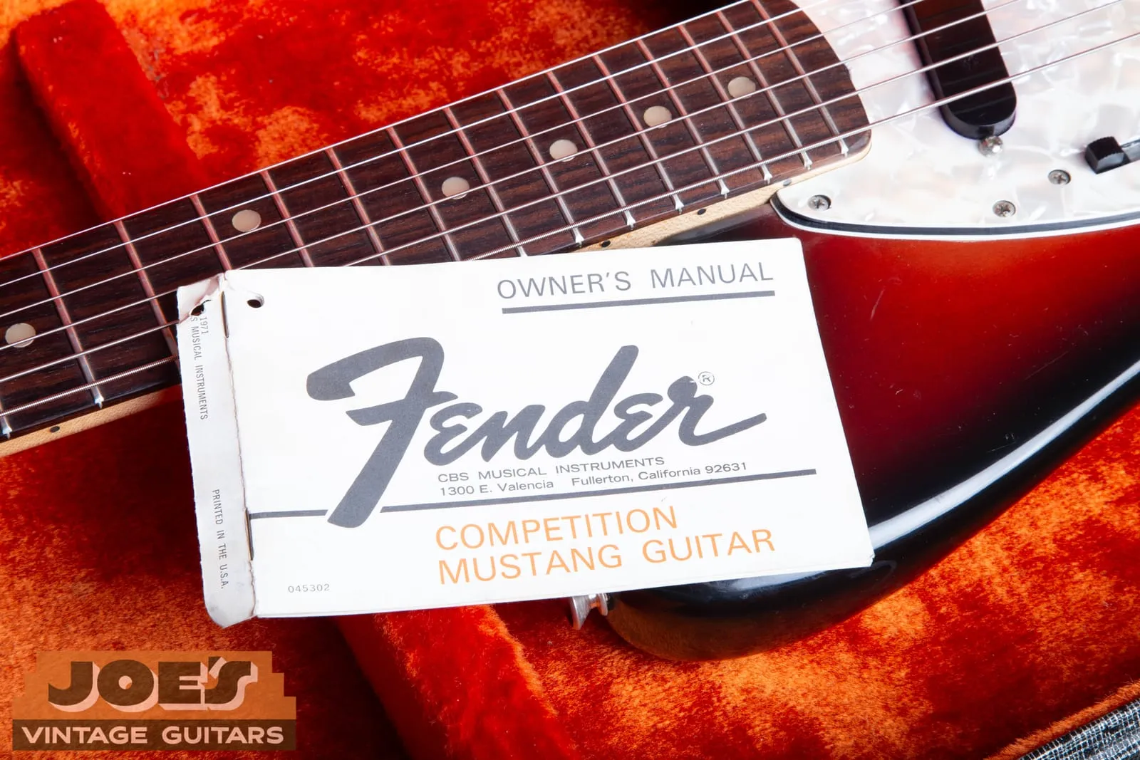 Original Fender Competition Mustang owner’s manual booklet lying on the orange plush lining of a vintage case.