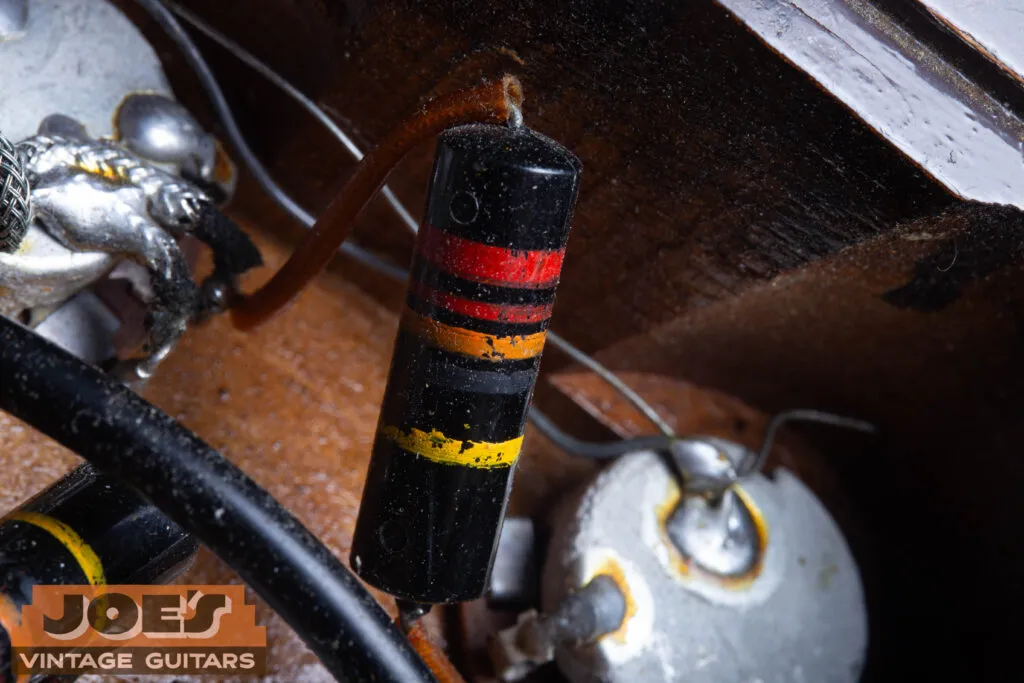 Macro close-up of an original 1956 Sprague “Bumblebee” capacitor (.022uF 400V) inside the control cavity, showing the distinct color-coded stripes.
