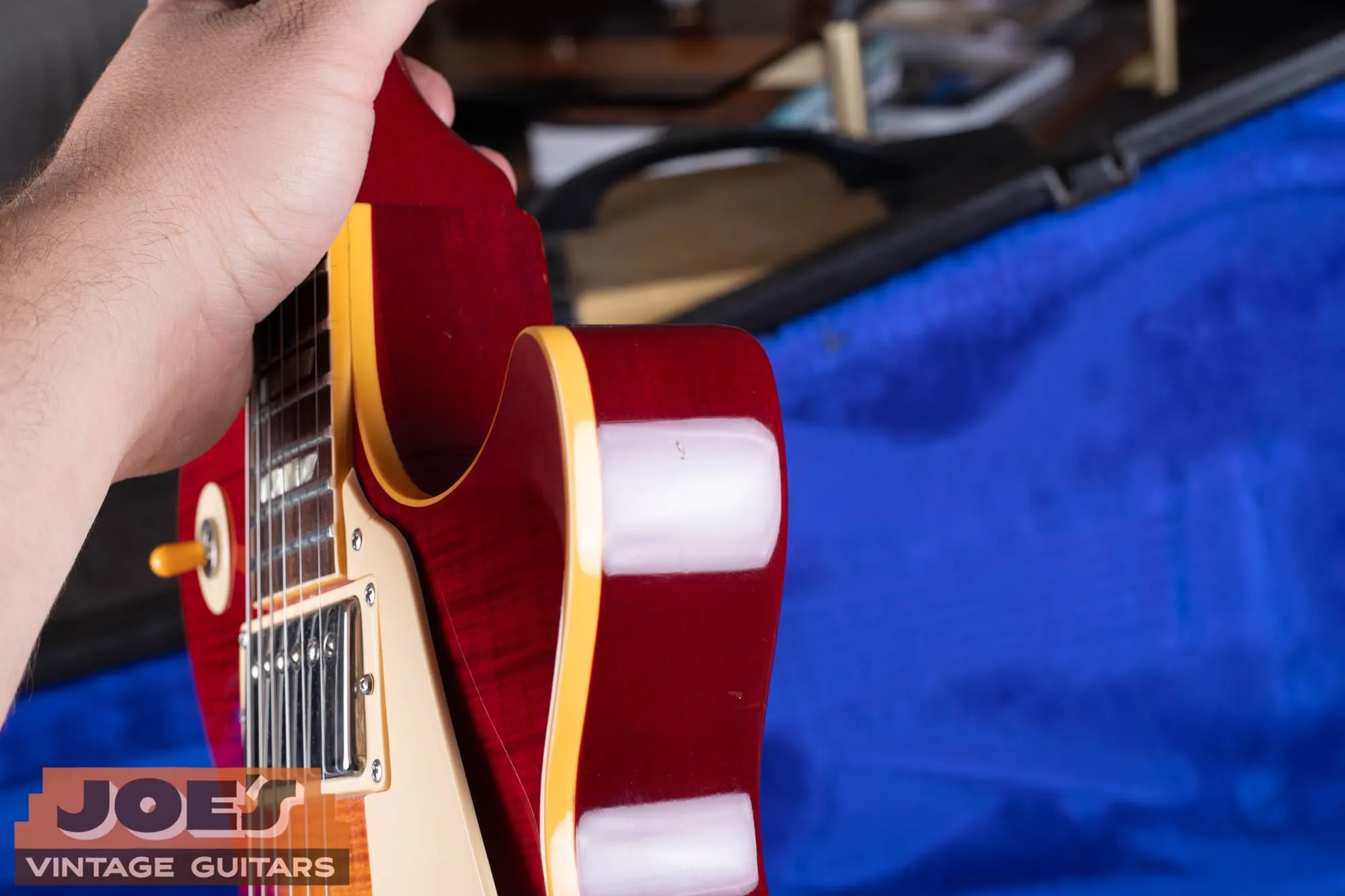 Side profile of a Gibson Aldo Nova Les Paul XPL showing the carved figured maple top, cream body binding, and translucent cherry mahogany back.