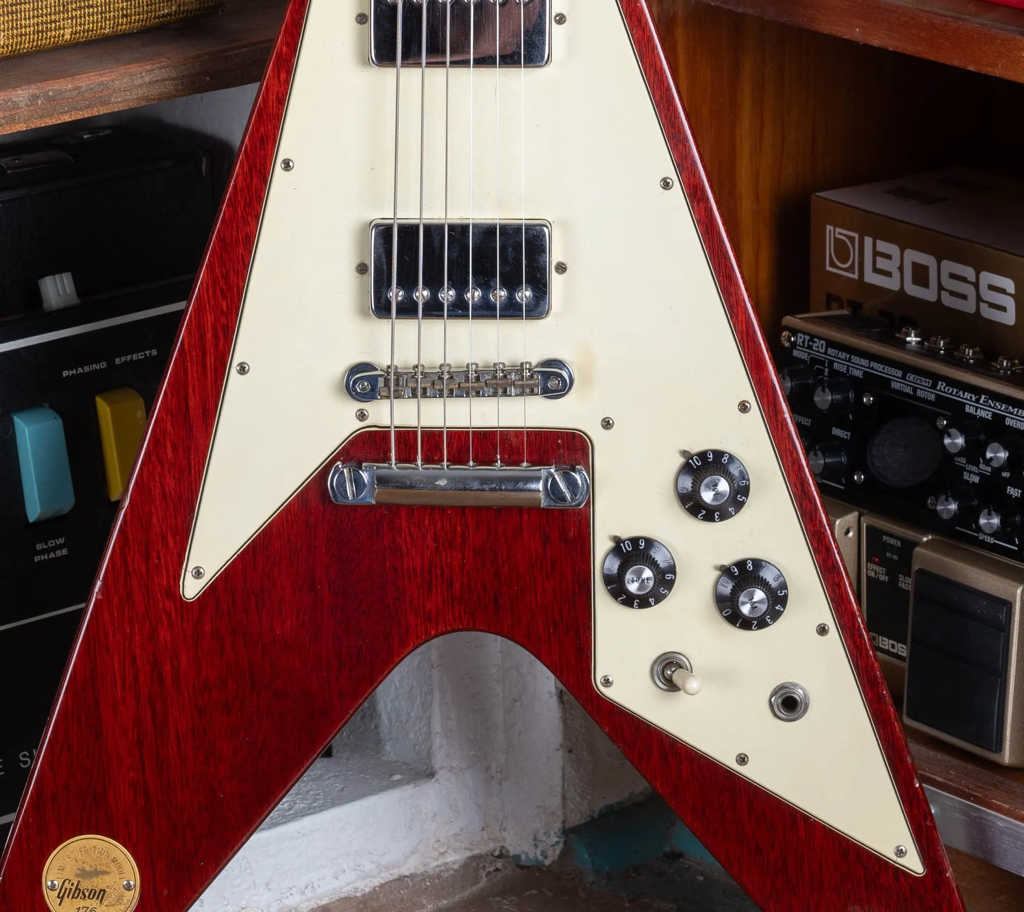 Upper body of a 1971 Gibson Flying V Medallion showing the ABR-1 Tune-o-Matic bridge, the separate chrome stop-bar tailpiece, two chrome humbuckers, the cream pickguard, and the black bonnet control knobs with the three-way toggle.