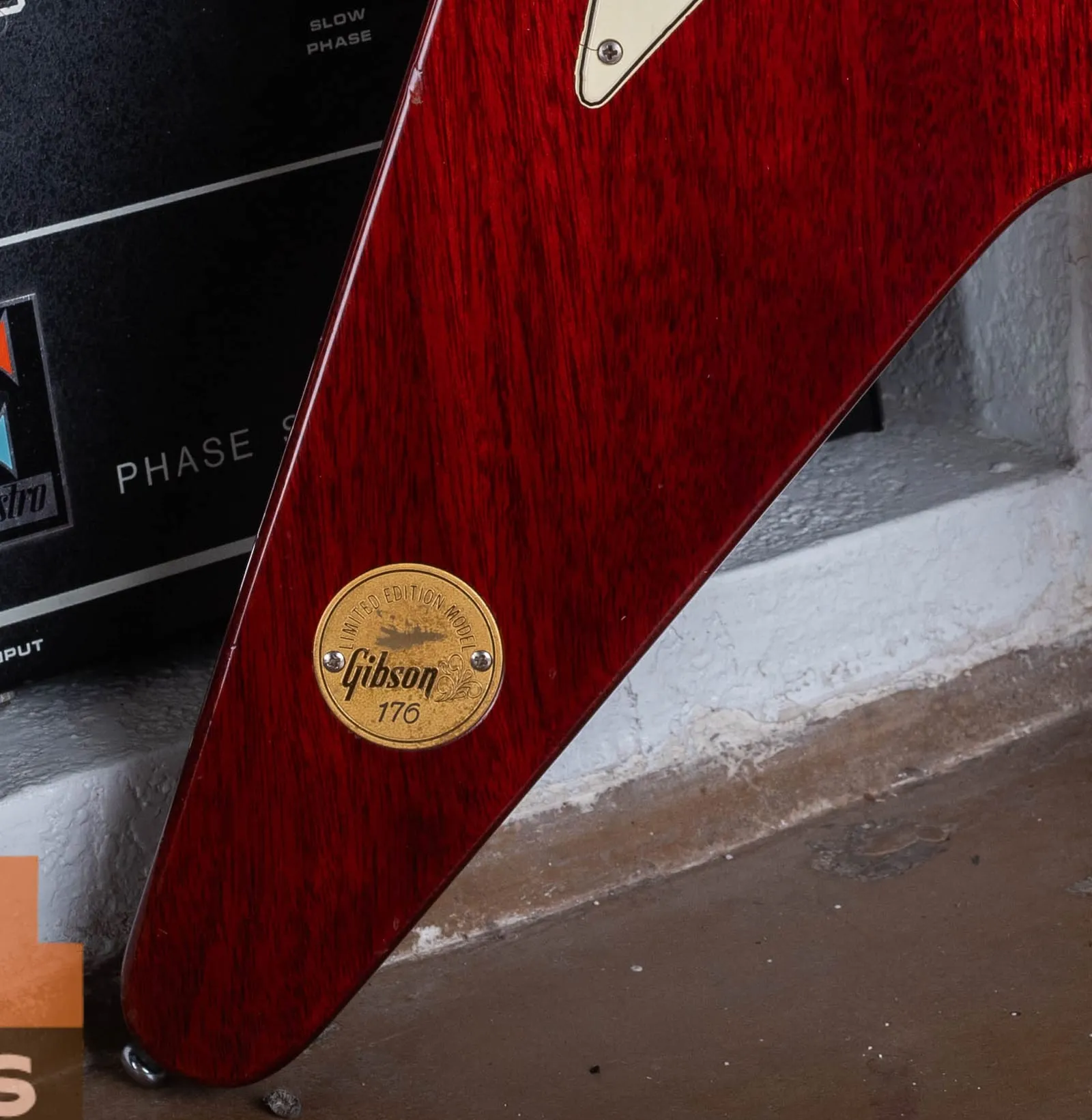 Close-up of the gold medallion coin set into the cherry mahogany wing of a 1971 Gibson Flying V, engraved with the words Limited Edition Model around the top, a small eagle, the Gibson script logo, and the hand-stamped number 176.