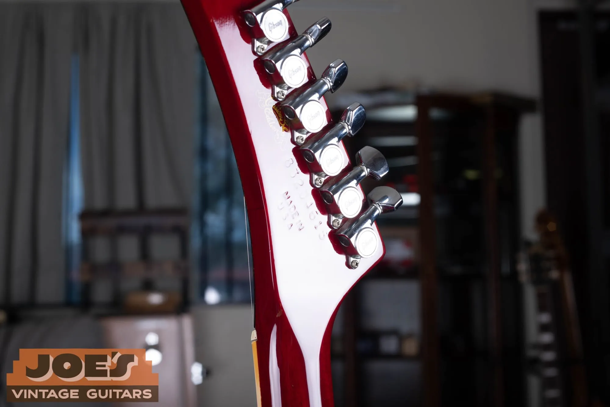 Back of a Gibson Les Paul XPL headstock in translucent cherry, showing the gold Custom Shop Edition decal, an impressed eight-digit serial number, Made in U.S.A. stamp, and chrome Gibson tuners.