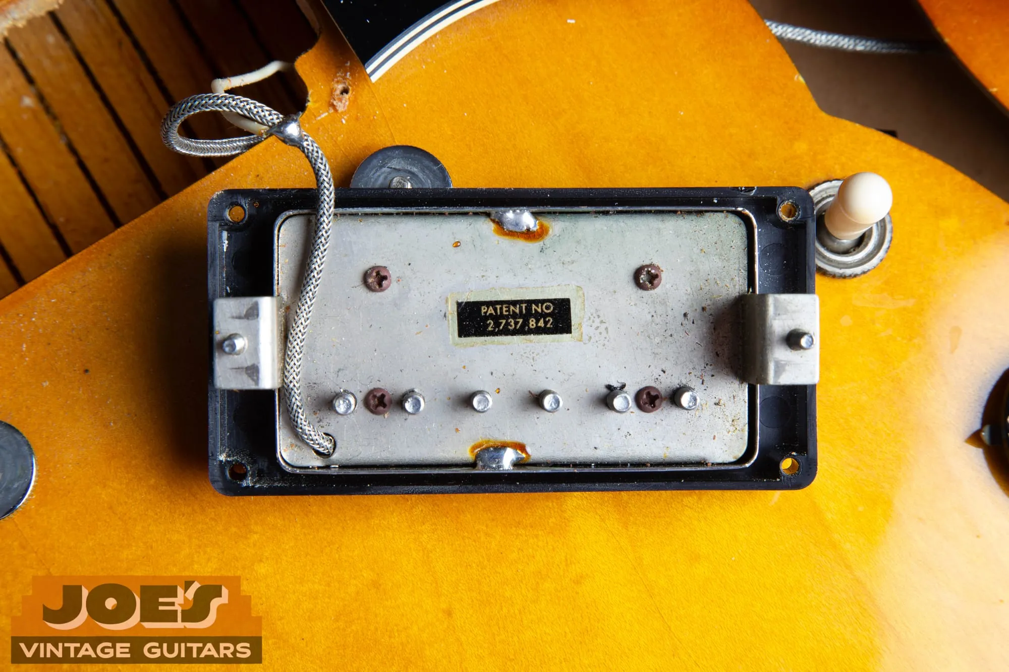 Underside of a Gibson patent number pickup showing the black and gold Patent No 2,737,842 sticker on the nickel silver baseplate.