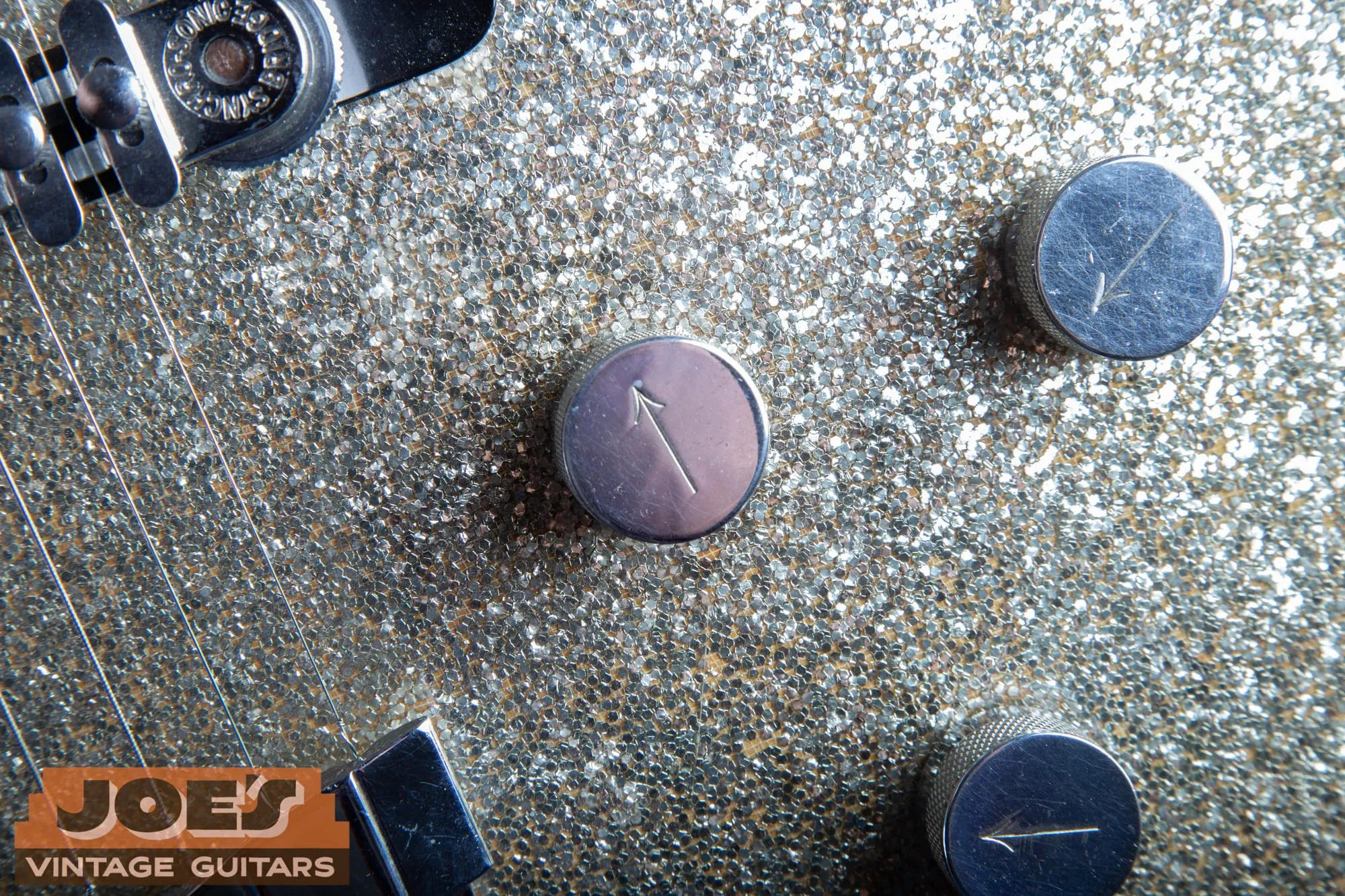 Close-up of two Gretsch arrow control knobs with engraved pointers and no G logo, on the silver sparkle top of a vintage Silver Jet.