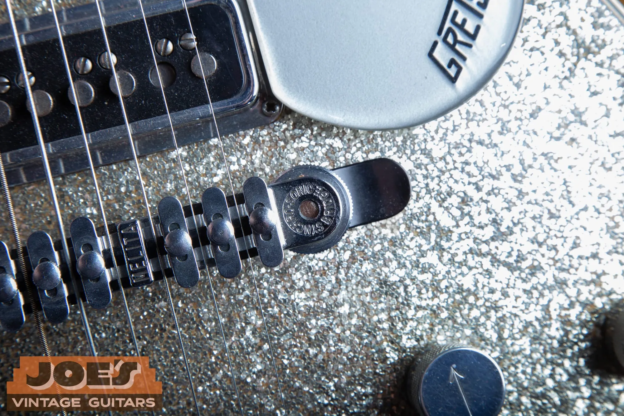 Close-up of a Melita Synchro-Sonic bridge stamped MELITA on a vintage Gretsch Silver Jet with a sparkle top.