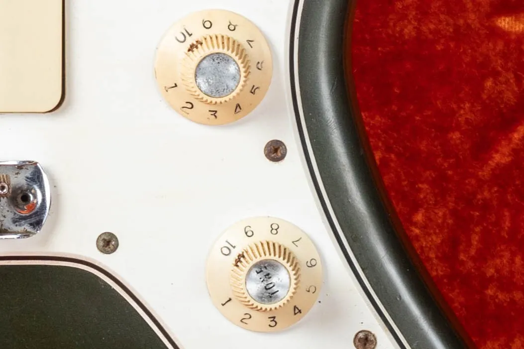 Fender Jazzmaster witch hat knobs close-up, white plastic with chrome domed top, CBS era indicator introduced mid-1965 replacing the skirted Strat-style knobs