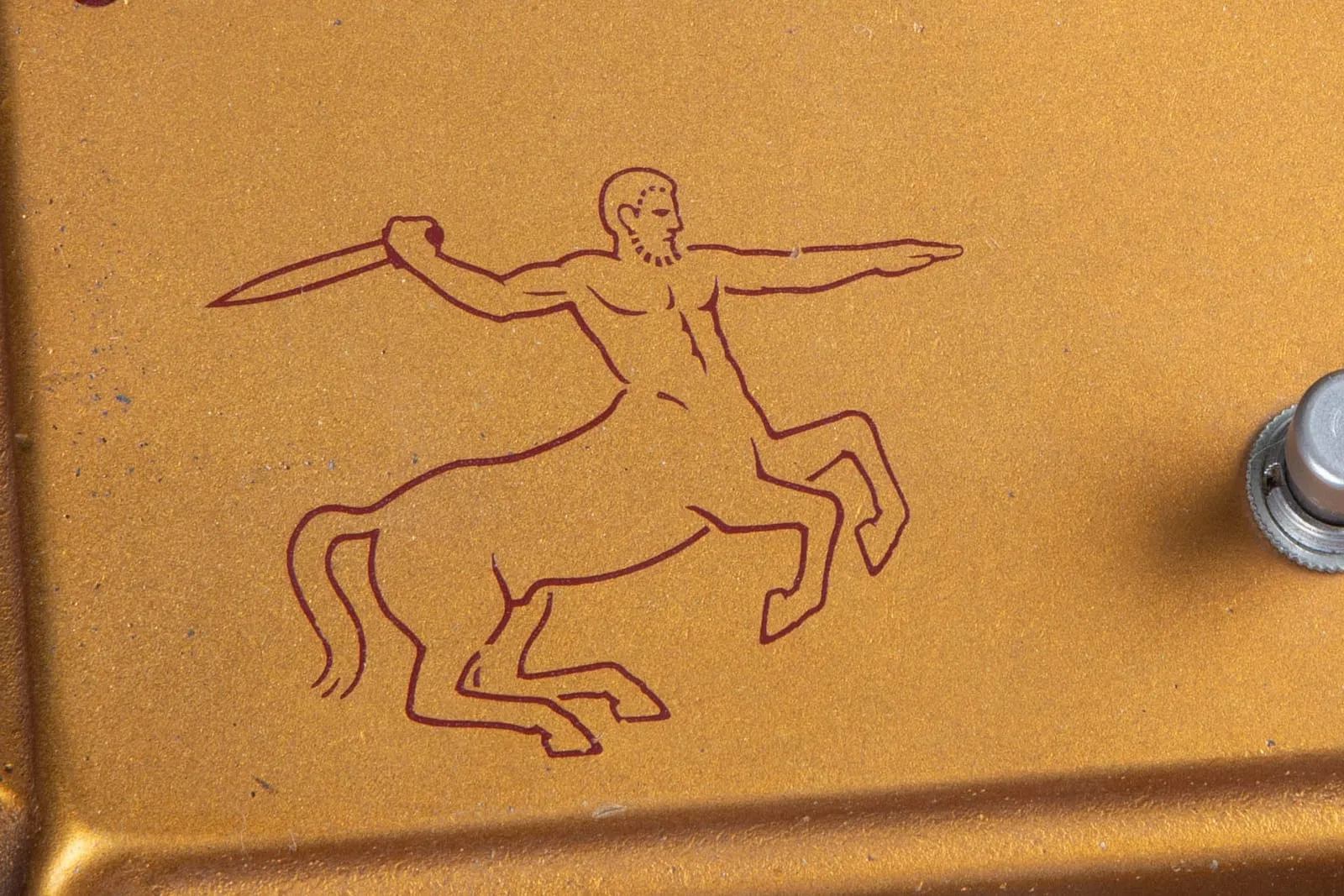 Close-up of the red centaur archer graphic on a gold Klon Centaur, showing the small figure with a short three-strand tail.