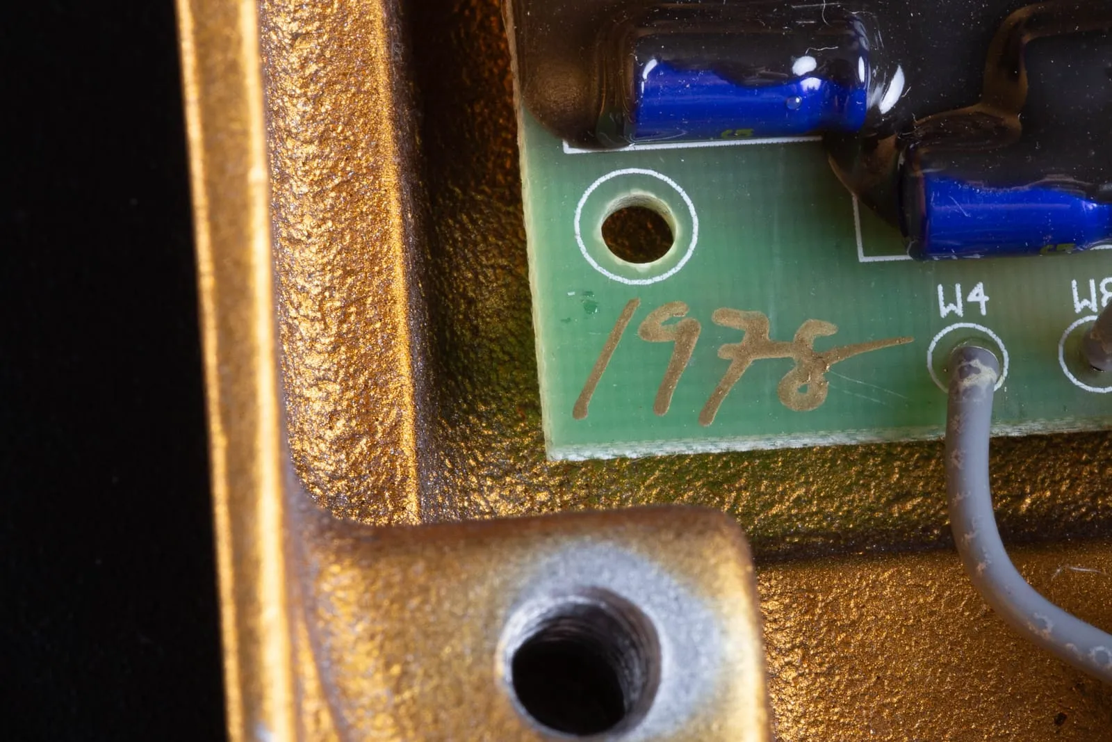 A handwritten gold serial number reading 1978 on the green circuit board of a Klon Centaur, inside the rough gold cast enclosure.