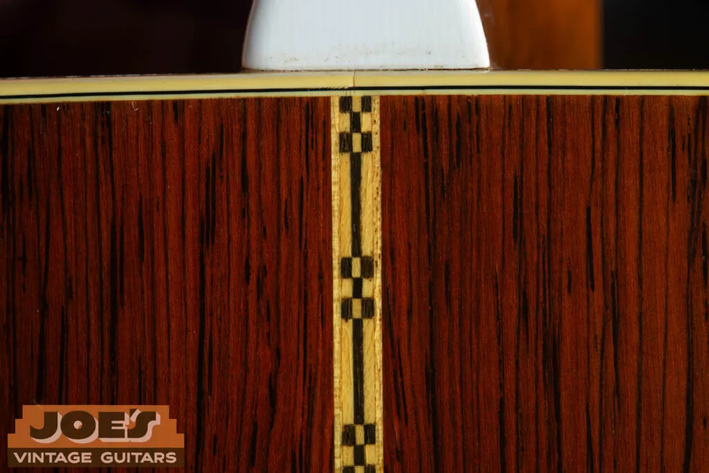 Close-up of the vintage “checkerboard” or Z-pattern backstrip on a 1959 Martin D-28E with Brazilian Rosewood. This decorative mosaic strip is a hallmark of the D-28E and is notably absent on the mahogany-backed D-18E.