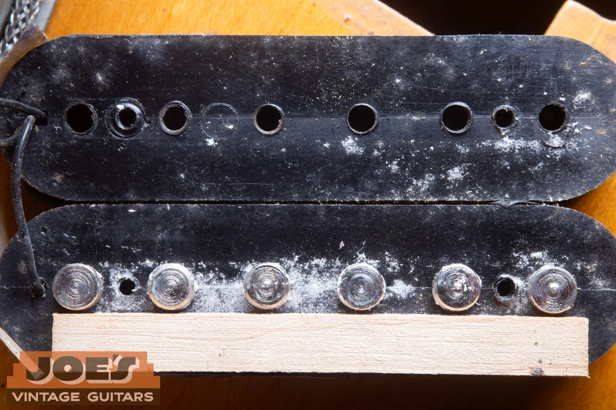 Undersides of two PAF bobbins showing the pole holes, small square tooling holes, and the maple spacer strip.