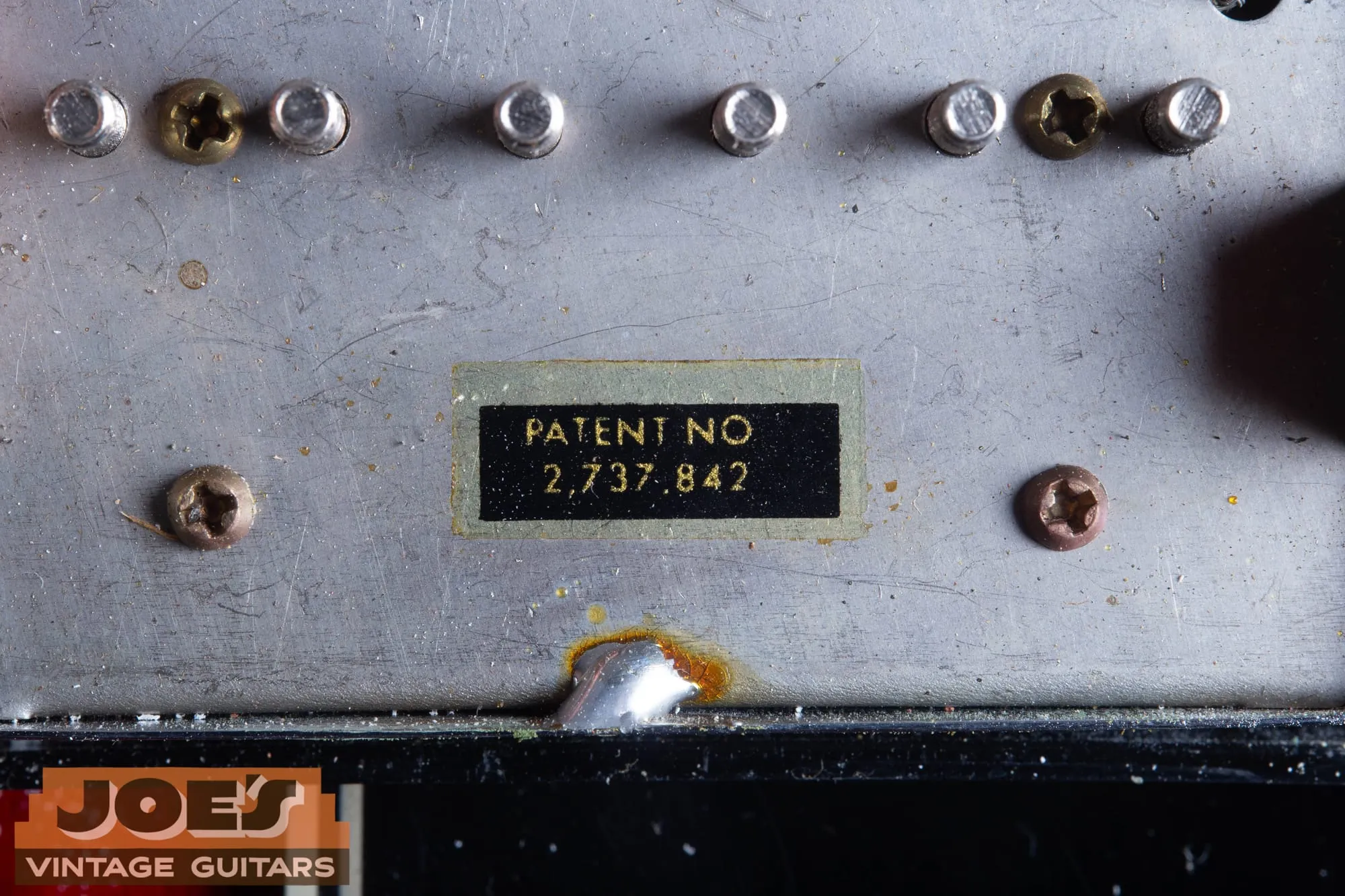Macro photo of an original Patent No 2,737,842 decal showing the yellowed clear carrier film around the black printed rectangle.