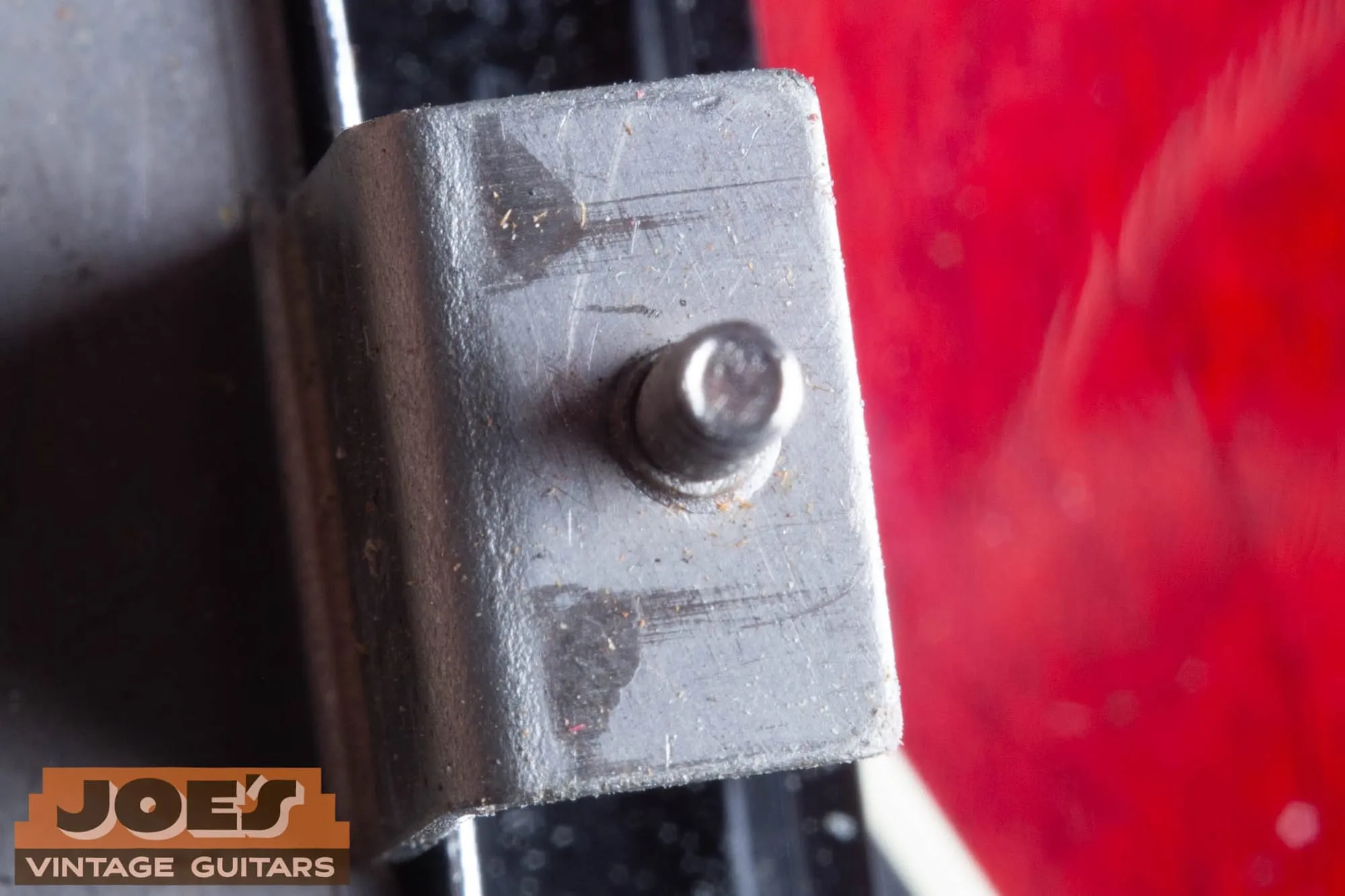 Close-up of a Gibson humbucker mounting leg showing rough factory tool marks and shear texture.