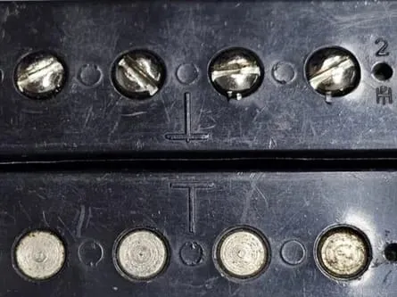 Two Gibson T-top humbucker bobbins showing the raised molded T beside the pole holes.