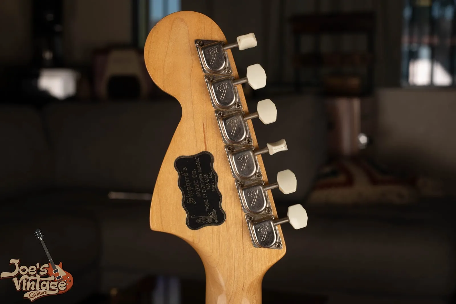 Back of a vintage Fender Mustang headstock showing the maple neck, string tree, and tuners.